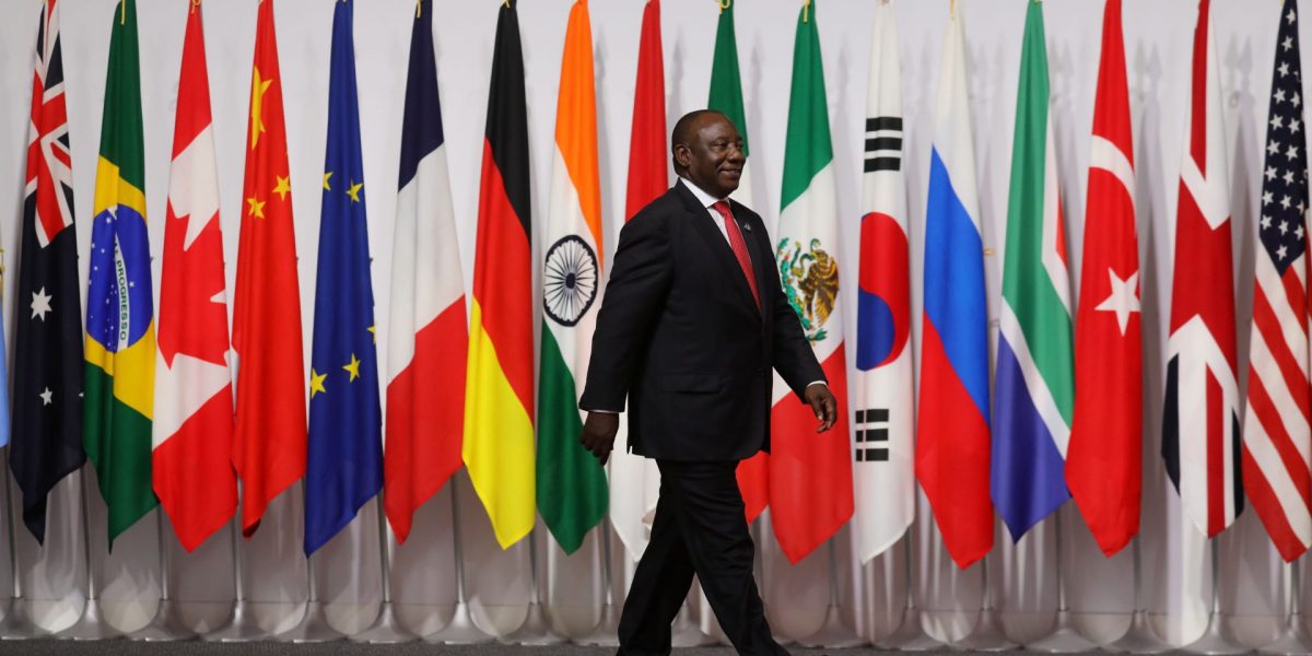 President Cyril Ramaphosa walking with country flags behind him