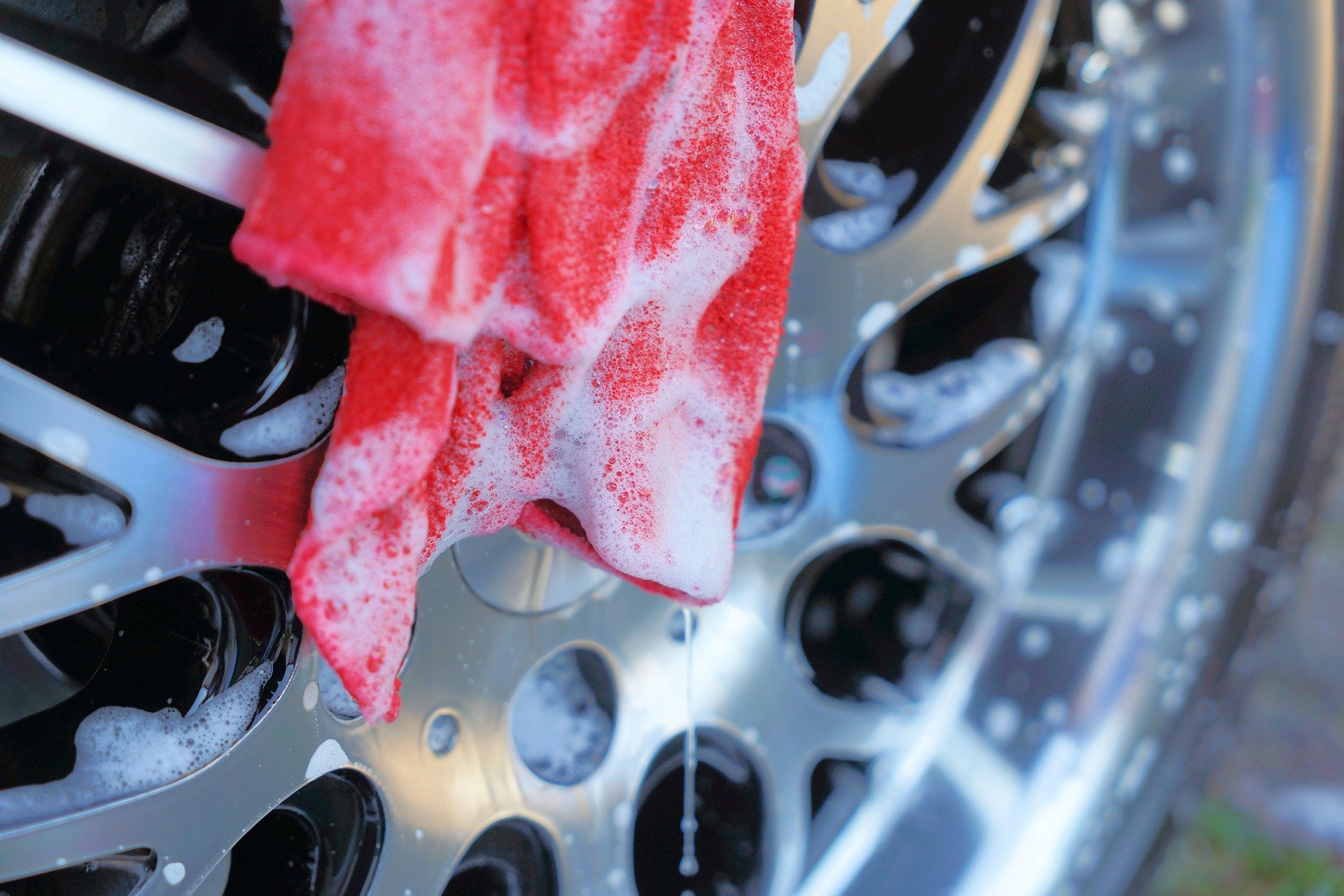 a red cloth with soap cleaning a car tyre